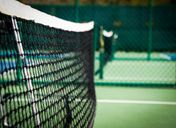 An empty pickleball court with a white net on a green surface