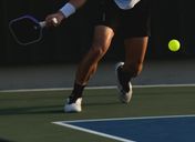Player swinging a pickleball paddle mid-rally on an outdoor court