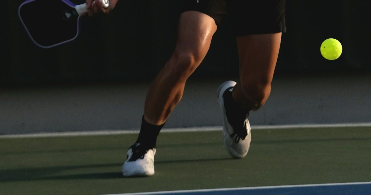Player swinging a pickleball paddle mid-rally on an outdoor court