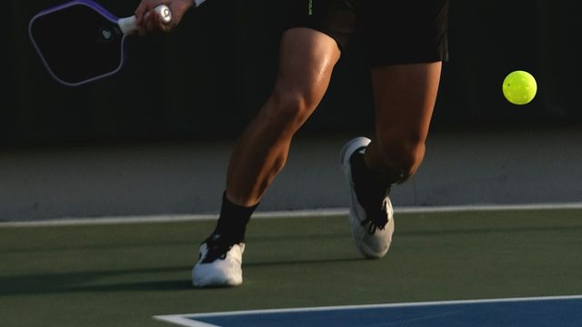 Player swinging a pickleball paddle mid-rally on an outdoor court