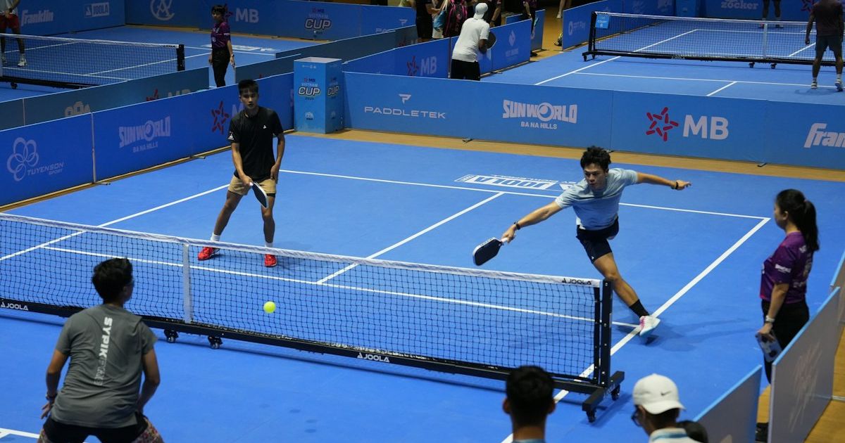 Players competing in a pickleball match on blue courts