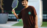 Player holding a pickleball paddle on an outdoor court